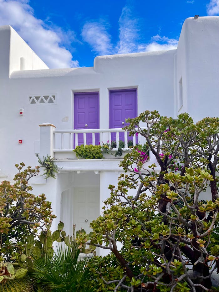 Crafting Captivating Headlines: Your awesome post title goes here A white house with purple doors and a vibrant garden under a bright blue sky, perfect for architectural inspiration.