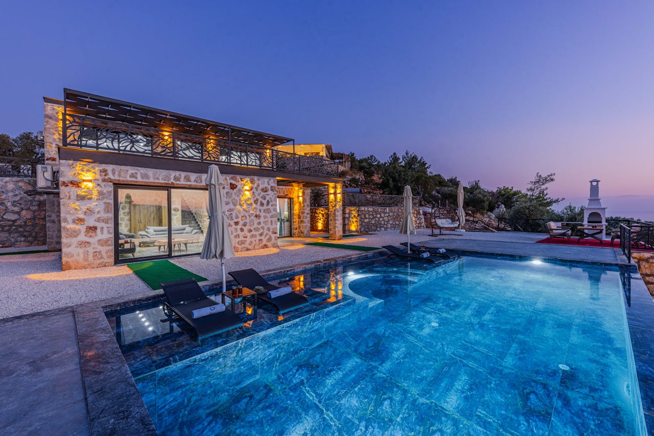 Elegant stone villa with infinity pool offers serene vacation vibes at twilight.