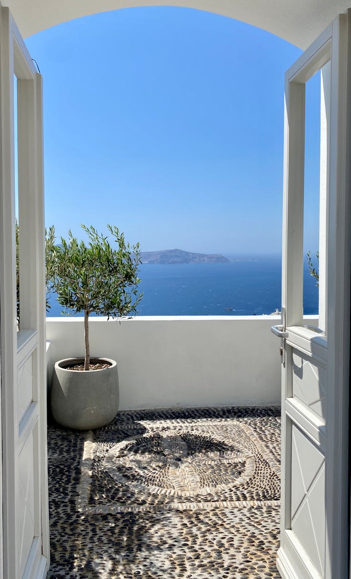 why-choose-us Open doors revealing a breathtaking view of the Aegean Sea from a Fira balcony.
